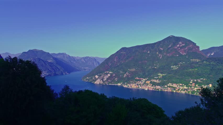 Carona, Switzerland – September 26 2022: High view from Monte San Salvatore overlooking Campione d’Italia, Lake Lugano, Monte Brè and distant alpine ridges.
