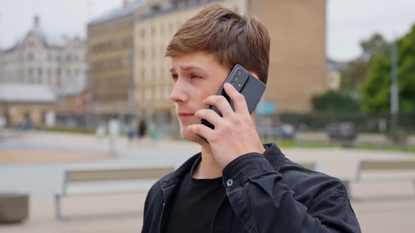 A young man speaks on the phone, looking tense and serious, as if raising his voice. - Powered by Shutterstock - Get 15% off with code: PIKWIZARD15