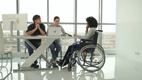 Teamwork brainstorm. Diverse multiracial colleagues woman in chair for people with disability working together. Group of people sitting in creative office discussing business. Young professional team - Powered by Shutterstock - Get 15% off with code: PIKWIZARD15