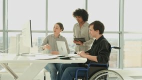Teamwork brainstorm. Diverse multiracial colleagues man in chair for people with disability working together. Group of people sitting in creative office discussing business. Young professional team - Powered by Shutterstock - Get 15% off with code: PIKWIZARD15