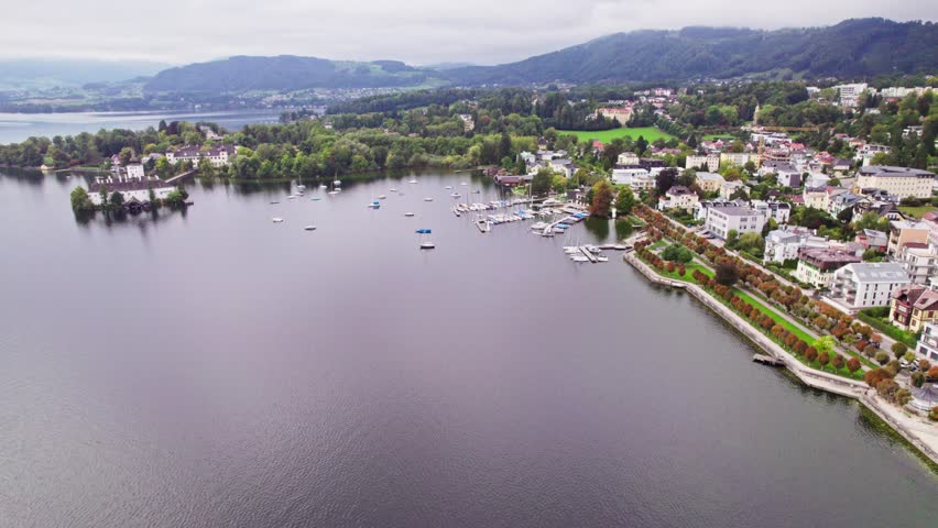 Drone approach to Gmunden yacht harbor with autumn park and coastline

