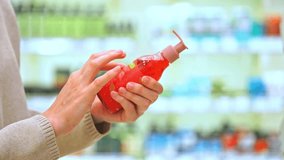 Customer reading shampoo label in cosmetics aisle, examining ingredients on a red pump bottle while choosing the best skincare and haircare product. - Powered by Shutterstock - Get 15% off with code: PIKWIZARD15