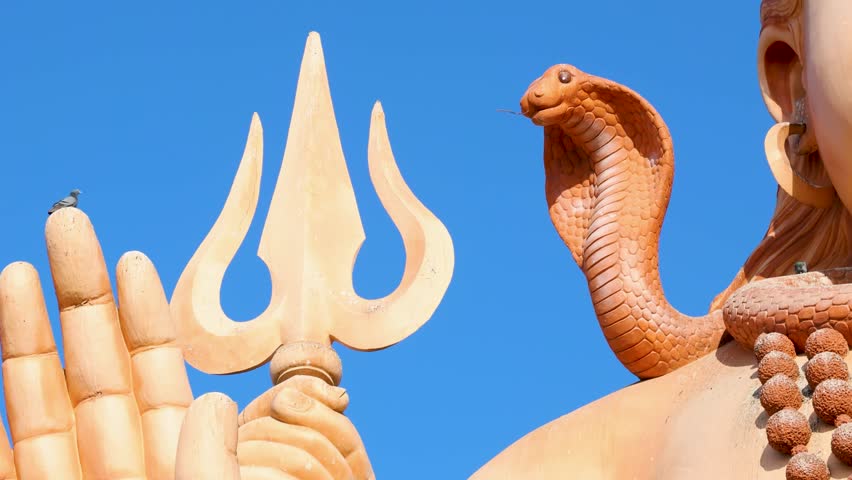 detailed view of shiva’s trident and snake hood against clear blue sky