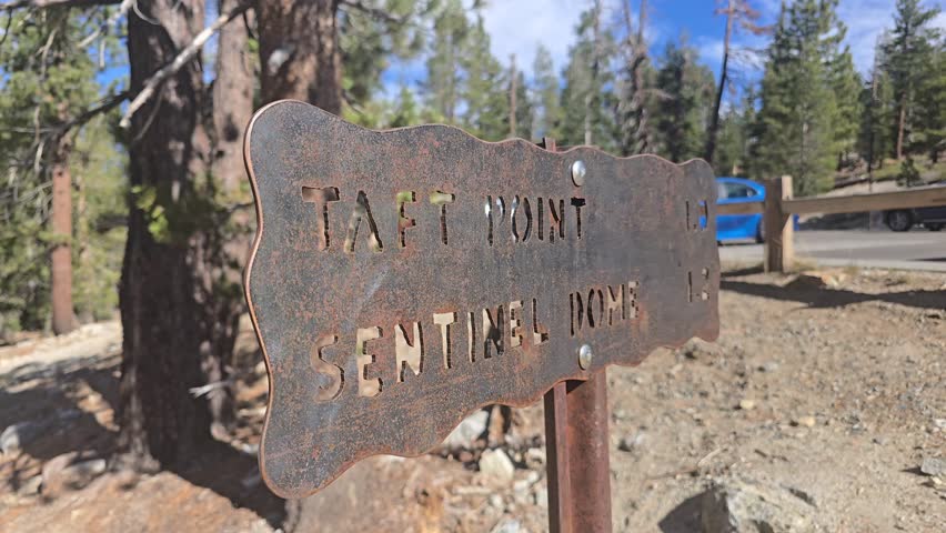 Rustic metal sign indicating directions to Taft Point and Sentinel Dome in a forest setting.