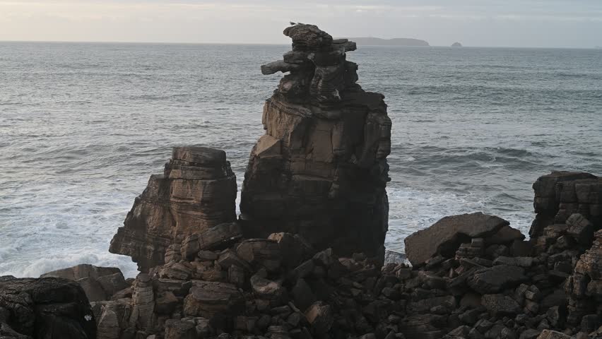 Tall coastal rock pillars rise above Atlantic waters near Peniche, filmed on November 9 2025 in soft daylight highlighting rugged geological structures, calm waves, and natural shoreline textures.