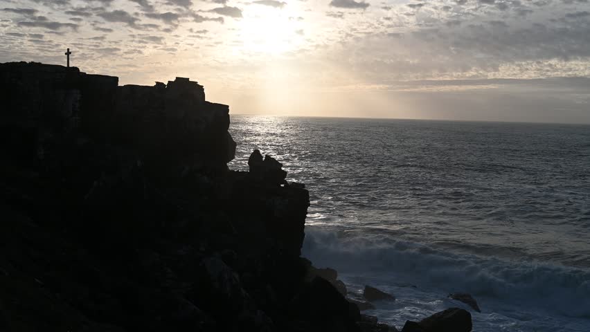 Ocean waves crash against rugged coastal cliffs under soft sunset light, capturing the dramatic shoreline and natural textures of the Atlantic coast in Peniche Portugal.