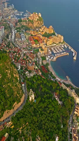  Aerial view of the city center of Monaco. Establishing shot showcases luxury yachts moored in Monaco Bay, the Palais Princier de Monaco, and luxury apartment buildings of Monte Carlo