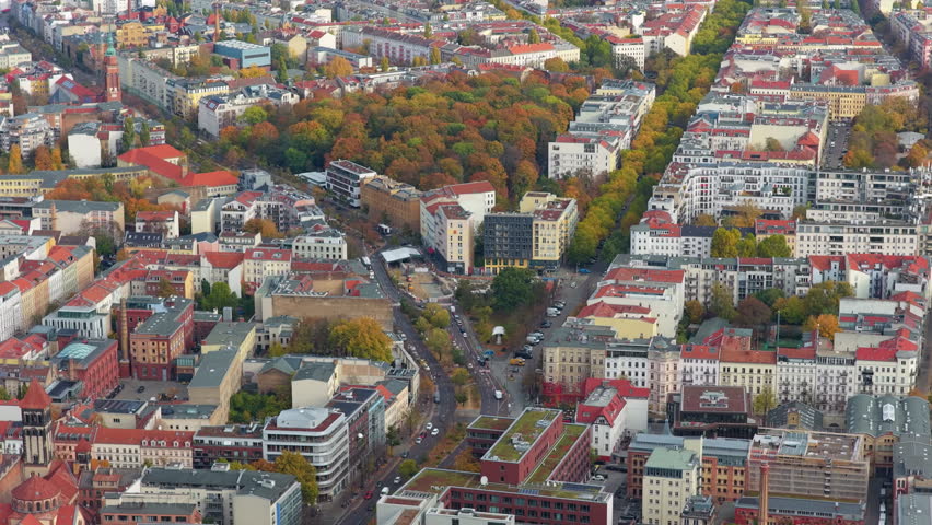 High angle perspective revealing residential buildings, streets with traffic, and city park with colorful autumn trees in Berlin, Germany
