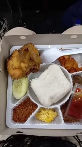The menu contains rice, fried chicken, sliced ​​cucumber, chili potatoes, omelette, chili sauce and several other side dishes served in a lunch box.