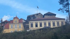 The national flag of Bosnia and Herzegovina waving in the wind atop the stone walls of the medieval Jajce Fortress (Citadel). Blue and yellow flag with white stars flying against a sky background. - Powered by Shutterstock - Get 15% off with code: PIKWIZARD15