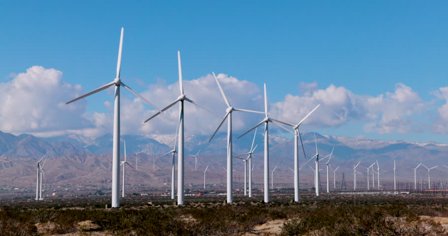 Static shot of wind turbines operating in the San Gorgonio Pass near Palm Springs, California. Renewable energy infrastructure in a desert mountain landscape under clear skies.
