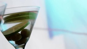 Front martini glass pulling in on opening, gold confetti falling, zooming to highlight lime, olives. Stemware, bartop, backlight, blue, bokeh, elegance, festive - Powered by Shutterstock - Get 15% off with code: PIKWIZARD15