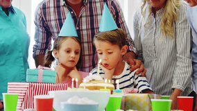 Kids leaning and blowing lit birthday cake candles, adults clapping as social icons rising at faces. Children, family, celebration, party, home, hats, joy - Powered by Shutterstock - Get 15% off with code: PIKWIZARD15