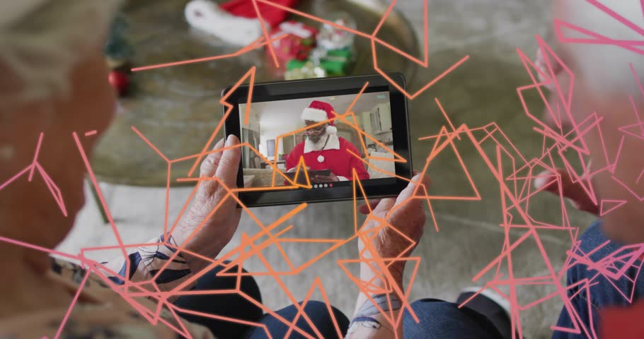 Seniors lifting tablet and watching Santa sharing holiday message, tech overlay obscuring tablet. Elderly, couple, screen, home, network, festive, gifts