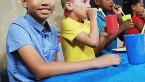 Boy in blue shirt smiling while confetti release covering kids wearing party hats at birthday. Children, celebration, table, balloons, gifts, colorful, laughter - Powered by Shutterstock - Get 15% off with code: PIKWIZARD15