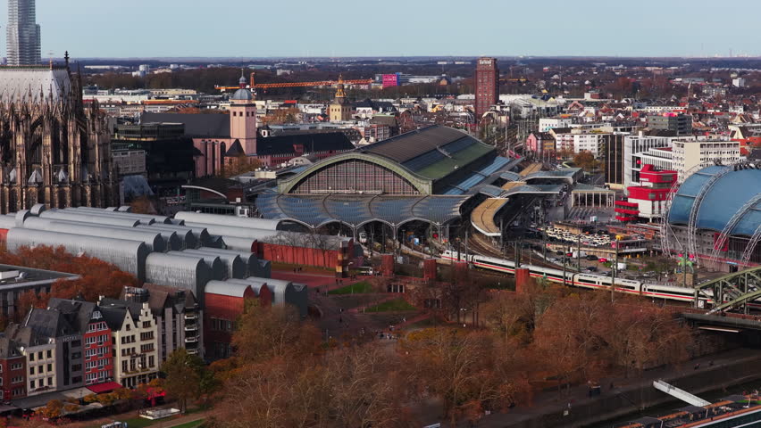 Aerial perspective of Cologne Central Station in Germany, with a high speed ICE train arriving and the famous cathedral nearby