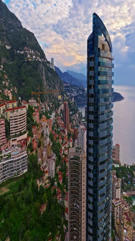  Aerial view of the city center of Monaco. Establishing shot showcases luxury yachts moored in Monaco Bay, the Palais Princier de Monaco, and luxury apartment buildings of Monte Carlo
