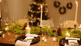 A detailed 4K view of a natural Christmas table setting, decorated with candles, moss, pinecones, and festive greenery. - Powered by Shutterstock - Get 15% off with code: PIKWIZARD15