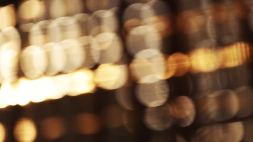 Slow motion footage of glowing yellow and orange bokeh circles forming soft abstract light background. 4K, selective focus.