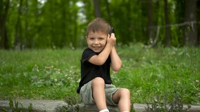 Three year old child sitting on curb in park talking on phone 4k - Powered by Shutterstock - Get 15% off with code: PIKWIZARD15