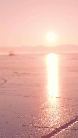 SUPER SLOW MOTION, CLOSE UP: Female skating on glittering surface of a frozen lake in golden sunset light. She is sliding on naturally frozen ice with her white skates on a beautiful sunny winter day.