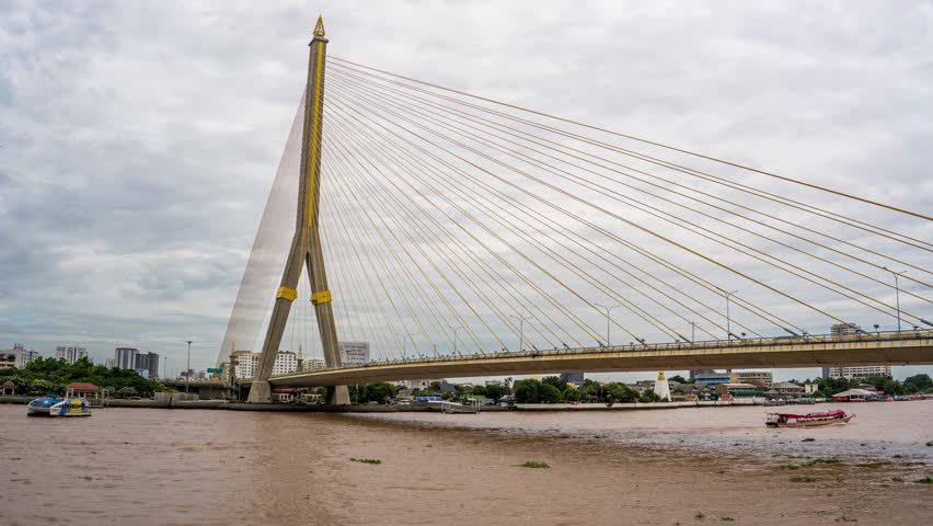 Comprehensive time-lapse featuring the complete structure of Rama VIII Bridge during an overcast morning with dramatic clouds in Bangkok, Thailand.