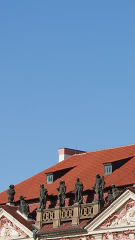 Baroque architecture, red rooftops, and saint statue under clear sky in Prague, Czech Republic