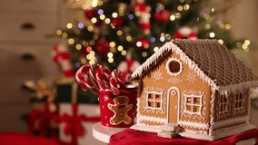 Gingerbread house and cup with candy canes on table against flashing blurred lights and falling glitter, closeup with space for text. Christmas atmosphere - Powered by Shutterstock - Get 15% off with code: PIKWIZARD15