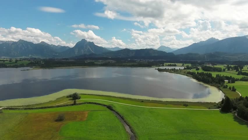 Scenic aerial view of a serene lake surrounded by lush green fields and mountains
