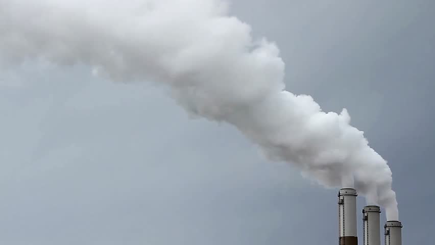 Industrial smokestacks releasing plumes of smoke into the overcast sky environment