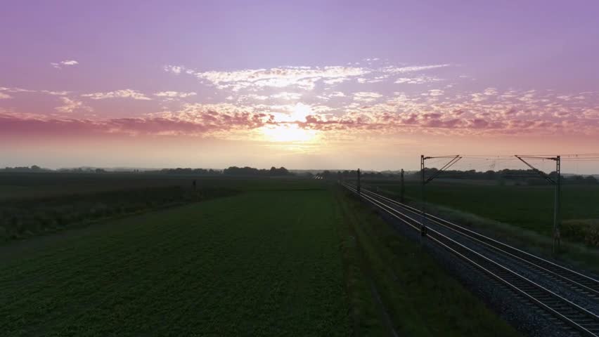 Railroad tracks stretch into the distance under a vibrant sunrise sky landscape