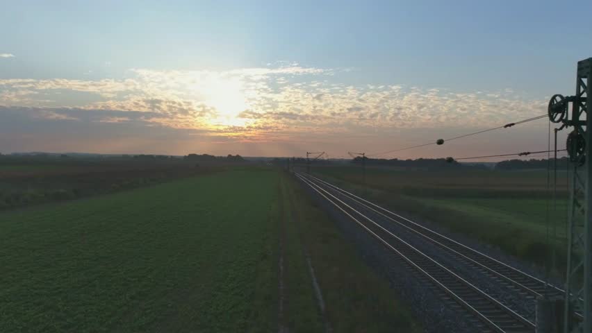 Railroad tracks stretch into the horizon under a vibrant sunset sky landscape