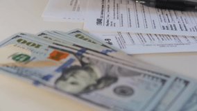 Close-up of US dollar bills, tax forms, calculator, and pen, depicting individual taxes, finance, and accounting processes. - Powered by Shutterstock - Get 15% off with code: PIKWIZARD15