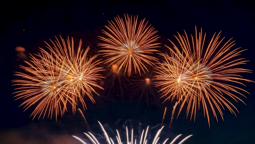 Multiple golden and white firework explosions light up the dark night sky during a festive celebration or event.