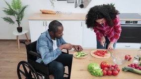 A diverse couple prepares a meal together in a bright, modern kitchen, with one person using a wheelchair. - Powered by Shutterstock - Get 15% off with code: PIKWIZARD15