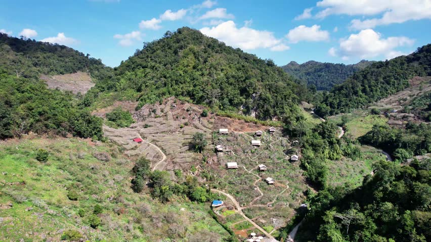 High-altitude drone shot gliding over the white tent-style homestay in Mu Nau, Moc Chau, revealing the sweeping mountain ranges and dramatic highland scenery.