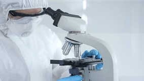 Medical virologist in a hazmat suit, mask, and gloves, diligently working at a microscope in a laboratory researching viruses. Healthcare and science concept - Powered by Shutterstock - Get 15% off with code: PIKWIZARD15