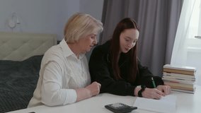 Experienced senior woman guiding young granddaughter while helping with homework, offering supportive mentoring and sharing educational wisdom at home learning environment - Powered by Shutterstock - Get 15% off with code: PIKWIZARD15