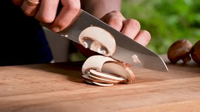 Horizontal slow-motion close-up of a fresh mushroom being sliced in an outdoor kitchen. Smooth knife movement, natural textures and a relaxed open-air cooking atmosphere. - Powered by Shutterstock - Get 15% off with code: PIKWIZARD15