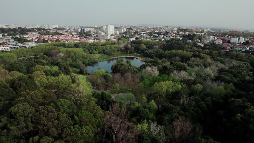 Expansive aerial view of Porto City Park - Parque da Cidade in Portugal featuring a central lake and walking paths and vast urban oasis contrasted with distant city skyline