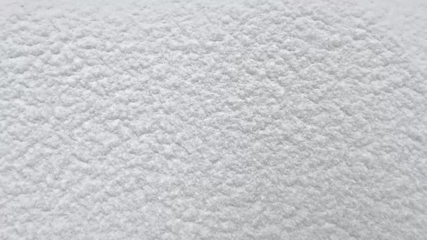 Hand continues drawing a full heart shape on smooth snow surface as the finger moves steadily forming clear lines while the camera holds close framing the completed symbol in bright winter light