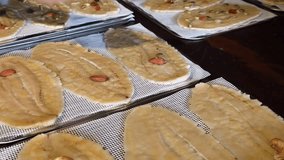 process of making a healthy snack, where a person's hand uses a small spoon to distribute various nuts, seeds, and dried fruits onto slices of flattened or dried banana. The slices are arranged  - Powered by Shutterstock - Get 15% off with code: PIKWIZARD15