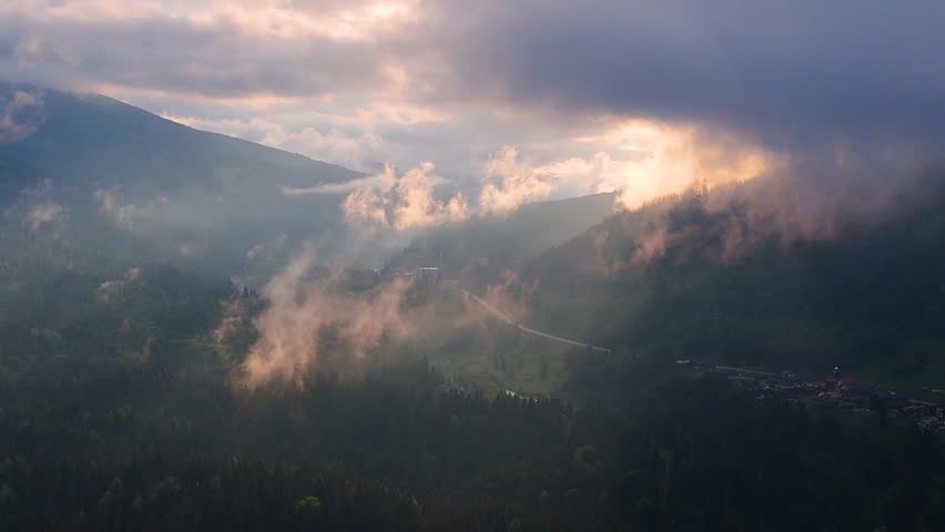 fog over the mountains at sunset, view from a drone