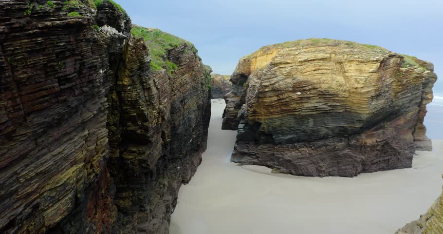 Aerial drone shot of the iconic natural arches and marine caves of Playa de las Catedrales in northern Spain. The video captures geological formations of this unique coastal scenery.