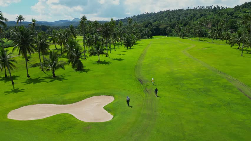 A rising aerial from the fairways toward the huge water puddle beside tropical trees in Canlubang Golf and Country Club, Calamba Laguna, Philippines