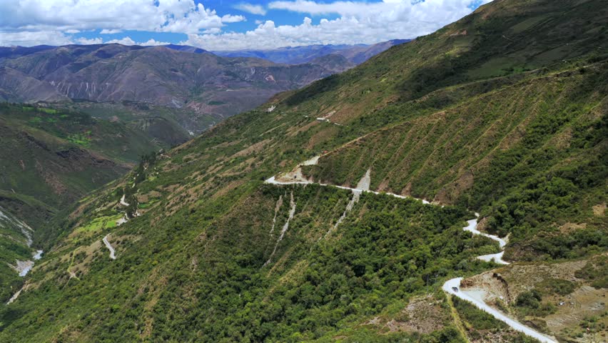 Car driving windy dirt road dust Soray Laguna Lake Humantay Sulcantay Trek Peru Perú aerial drone clouds blue skies high altitude elevation Peruvian Andes Mountain Range peaks forward follow motion