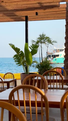 "Experience breathtaking oceanfront dining with stunning views of the turquoise sea and vibrant boats. Our open-air restaurant offers a serene escape with charming wooden furniture and tropical palms.