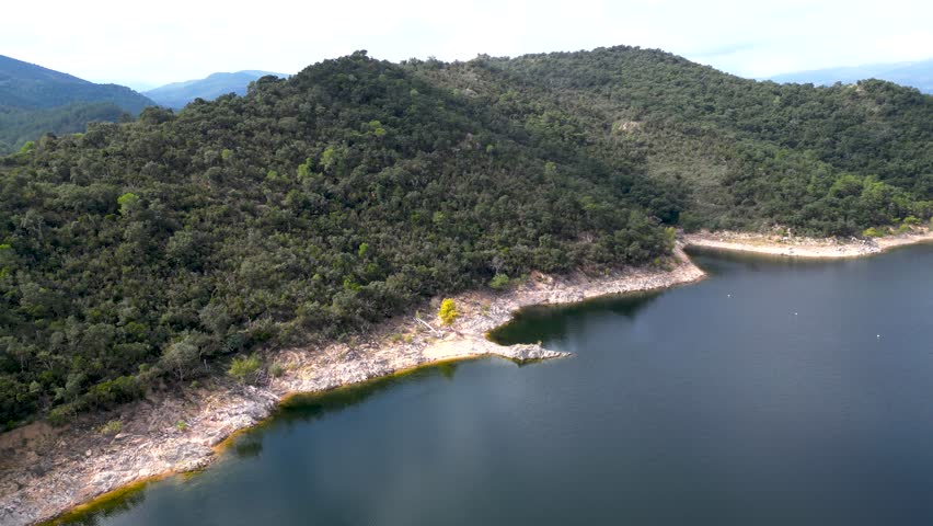 Drone flying over mountain lake and forested shoreline