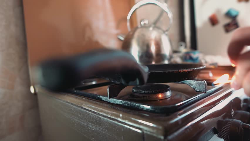 The frying pan is on the stove and a flame is burning under it. The process of making pancakes is underway.