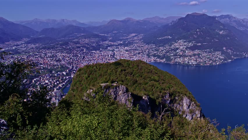 Lugano, Switzerland – October 24, 2022: Panoramic view from Monte San Salvatore over Lake Lugano, the city of Lugano, Monte Brè and distant alpine ranges.